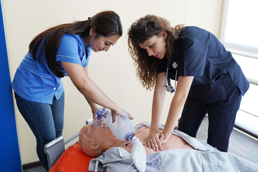 Two nursing students learn how to rescue patients using a CPR doll in a healthcare setting